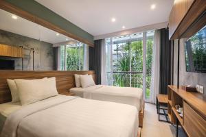 ein Hotelzimmer mit zwei Betten und einem Fenster in der Unterkunft Rimbun Canggu Hotel in Canggu + 79 Fotos