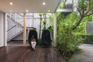 a man sitting in a chair in a room with plants at Rimbun Canggu Hotel in Canggu