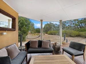 una veranda riparata con divani, tavolo e sedie di Aurora Cottages - Mountain View a Pomonal