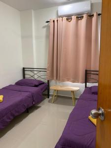 two beds in a room with purple sheets and a curtain at Igo homestay Subang Airport - Family Room in Shah Alam