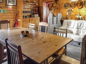 a wooden table and chairs in a room with a refrigerator at Cow Boy Cabin - Uk47145 in Glasgow