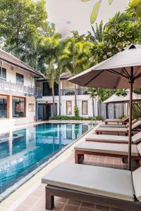einen Außenpool mit Stühlen und einem Sonnenschirm in der Unterkunft Amatak Boutique Hotel in Siem Reap