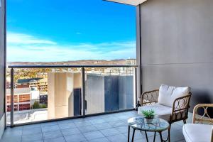 a balcony with a chair and a glass table at 'The Hindmarsh' Hotel-style Pad with Hills Panorama in Adelaide