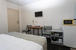 a hotel room with a bed and a table and chairs at Fig Tree Motel in Narrandera