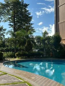a blue swimming pool with trees and a building at Travel and Lodge Palawan in Puerto Princesa City +8 photos