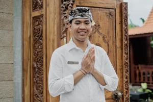 a man clapping his hands in front of a door at Ithaca Ubud Villa in Ubud +111 photos