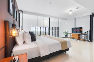 a bedroom with a large white bed and a television at Sovrae by Kozystay - Grogol in Jakarta