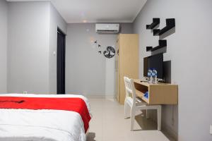 une chambre avec un lit et un bureau avec un ordinateur dans l'établissement RedDoorz near Jakarta International Velodrome, à Jakarta