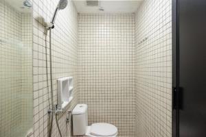 La salle de bains est pourvue de carrelage blanc, de toilettes et d'une douche. dans l'établissement RedDoorz near Jakarta International Velodrome, à Jakarta 39 autres photos