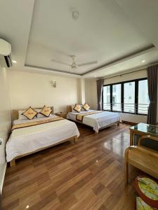 two beds in a room with wooden floors at TIẾN LUẬT in Cat Ba