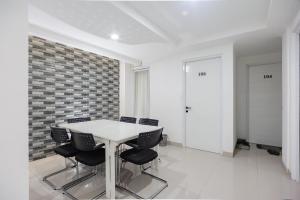 une salle à manger avec une table et des chaises blanches dans l'établissement RedDoorz near Jakarta International Velodrome, à Jakarta