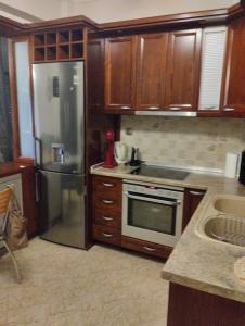 a kitchen with wooden cabinets and a stainless steel refrigerator at Linda's apartment in Agia Triada +3 photos