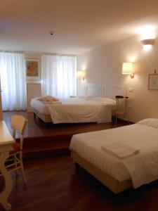 a hotel room with two beds and a desk at Hotel Atlantic in Bologna