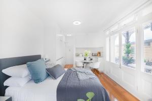 una camera bianca con letto e cuscini blu di Not your usual studio apartment a Sydney