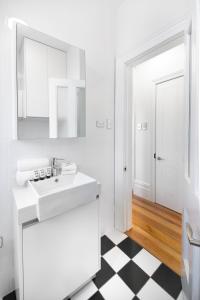 bagno con lavandino bianco e pavimento a scacchi in bianco e nero di Not your usual studio apartment a Sydney