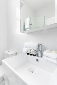 bagno bianco con lavandino e specchio di Not your usual studio apartment a Sydney