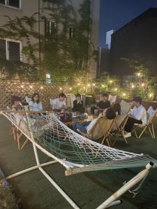 a group of people sitting in chairs in a hammock at hola! Hostel in Jeju