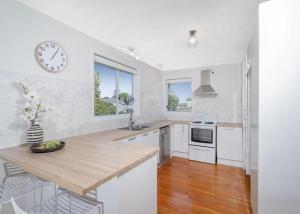 una cocina blanca con un reloj en la pared en Casa Blue, en Whitianga 10 fotos más