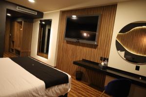 a hotel room with a bed and a flat screen tv at Hotel Yoru in Querétaro
