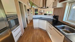 una cucina con armadi bianchi e un lavandino in acciaio inossidabile di Cozy And Modern Holiday Home With All Equipment a Neder Lysabild