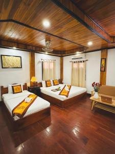 2 łóżka w pokoju z drewnianymi ścianami i drewnianą podłogą w obiekcie Luang Prabang Oudomlith Villa & Travel w mieście Luang Prabang