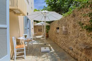 un patio con sombrilla, mesas y sillas en Villa Nika, en Spetses