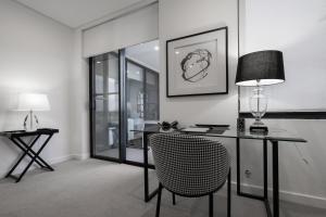 a room with a desk with a chair and a lamp at CBD Apartments by the International in Wagga Wagga