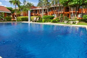 a large blue swimming pool in front of a building at Happy Oasis Second Floor Condo with Terrace in Coco +21 photos
