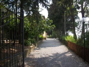 a gate leading down a street with trees and a sidewalk at Residence La Casina in Castagneto Carducci