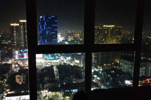 a view of a city at night from a window at nice apartment with city view at Grand Jati Junction in Medan