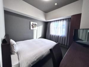 a bedroom with a bed and a flat screen tv at Hotel Route-Inn Morioka Minami Inter in Morioka