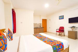 a bedroom with a bed and a red chair at FabExpress Mann Pasand Inn in Bangalore