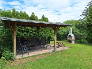 a wooden pergola with chairs and a table and a grill at Gaststätte und Pension Zur Schiene in Merseburg