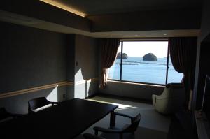 una stanza con tavolo e sedie e una grande finestra di Kochoran a Toba