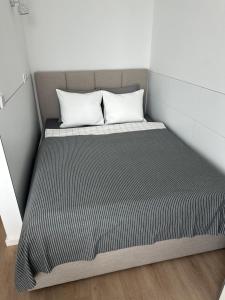 a bed in a small room with two pillows at Ozo eco apartments in Vilnius