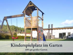 a wooden playground in a park with a swing at Fewo River, Stilvolles Ferienhaus für Familien großer Garten, Spielplatz, Sauna & Badefass in Wendisch Rietz +22 photos