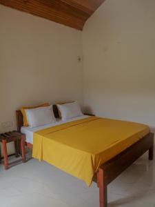 a bedroom with a bed with a yellow blanket on it at Serenity Sinharaja in Deniyaya