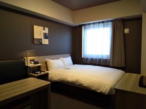 um quarto de hotel com uma cama e uma janela em Hotel Route-Inn Mihara Ekimae em Mihara