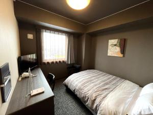 a bedroom with a bed and a desk and a television at Hotel Route-Inn Gifukencho Minami in Gifu
