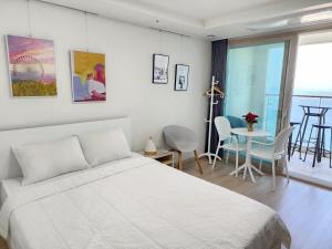 a white bedroom with a bed and a table and chairs at Sokcho Summitbay 1807 "Panoramic Ocean View" in Sokcho