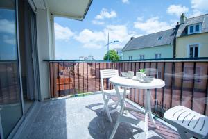 a balcony with a white table and chairs on it at Le Franc bord I Plage à 200m in Crozon