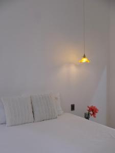 a white bed in a white room with a lamp at Gạo Homestay in Mui Ne