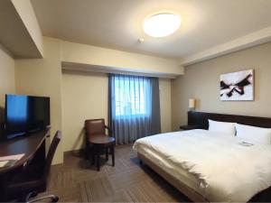 Habitación de hotel con cama, escritorio y TV. en Hotel Route-Inn Miyazaki Tachibana Dori en Miyazaki