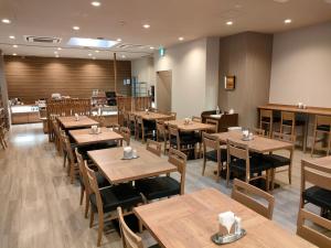 an empty restaurant with wooden tables and chairs at Hotel Route-Inn Miyazaki Tachibana Dori in Miyazaki