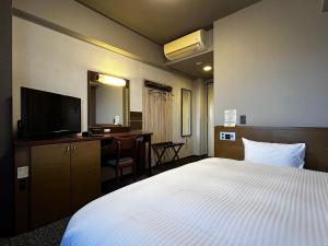 a bedroom with a bed and a desk and a television at Hotel Route-Inn Marugame in Marugame