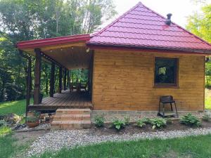 a small wooden cabin with a red roof at Dom całoroczny in Wojsławice