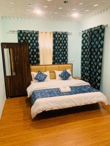 sypialnia z dużym łóżkiem z niebieskimi zasłonami w obiekcie Faizzy's residency w mieście Śrinagar