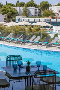 una mesa y sillas junto a una piscina en MarSenses Natura Olea Hotel en Cala D'Or