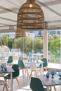 un ristorante con tavoli, sedie e ampie finestre di MarSenses Natura Olea Hotel a Cala d´Or