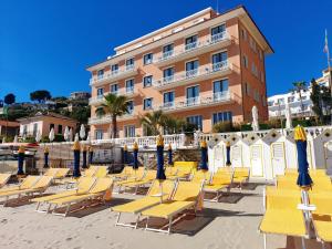 a row of yellow beach chairs in front of a building at Hotel Golfo e Palme in Diano Marina